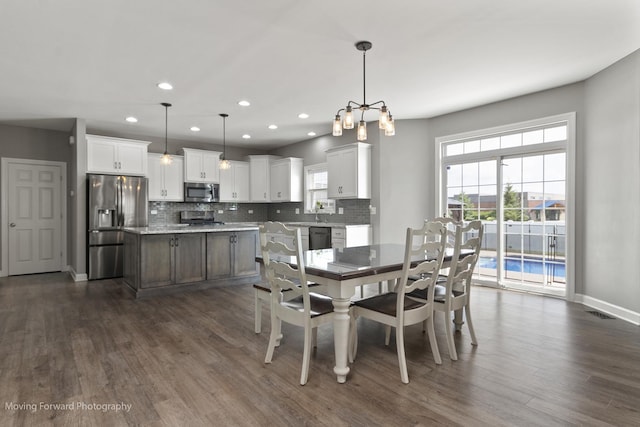 dining area with plenty of natural light, dark hardwood / wood-style floors, and a notable chandelier