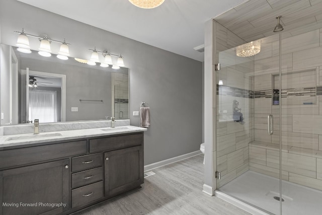 bathroom featuring ceiling fan, an enclosed shower, vanity, wood-type flooring, and toilet