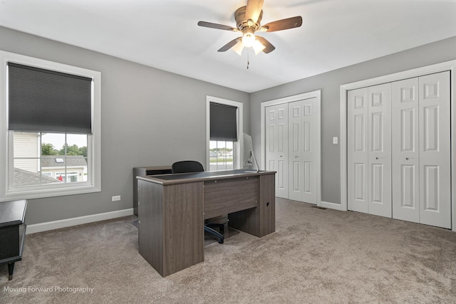 carpeted office with ceiling fan and plenty of natural light