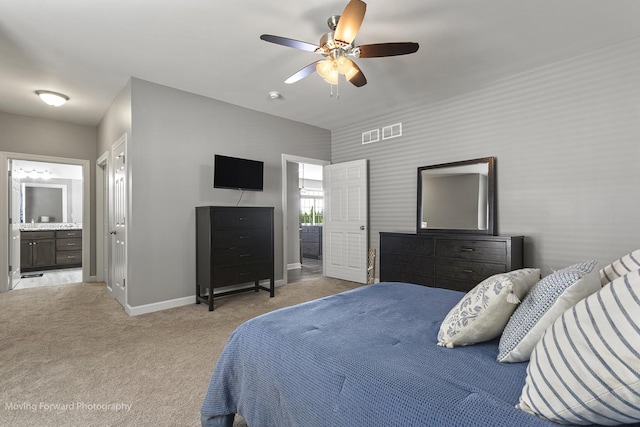 bedroom with ceiling fan, ensuite bath, and light carpet