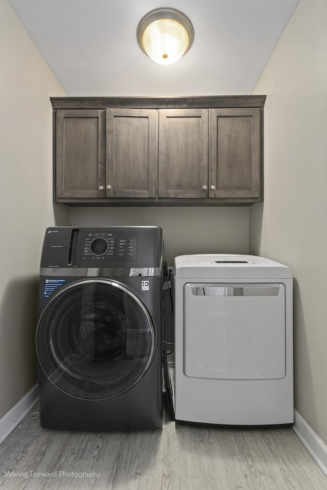 clothes washing area featuring cabinets, independent washer and dryer, and light hardwood / wood-style flooring