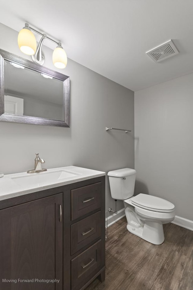 bathroom with wood-type flooring, vanity, and toilet