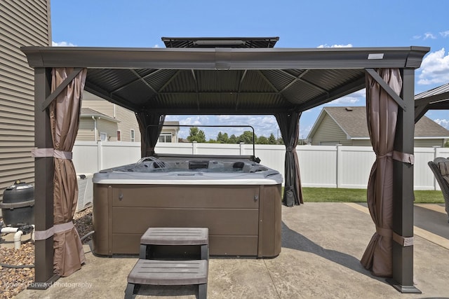 view of patio / terrace featuring a hot tub and a gazebo