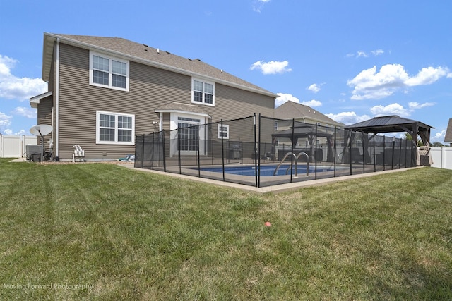 rear view of property with a fenced in pool, a gazebo, and a lawn