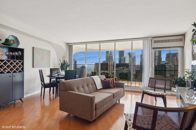 living room featuring a wall of windows, wood-type flooring, and plenty of natural light