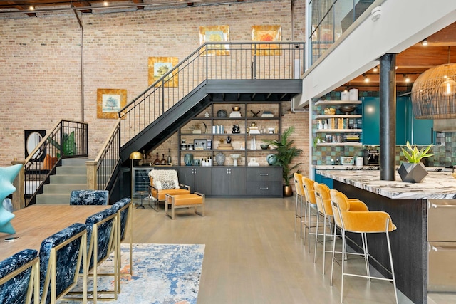 interior space with a towering ceiling, brick wall, and light hardwood / wood-style floors