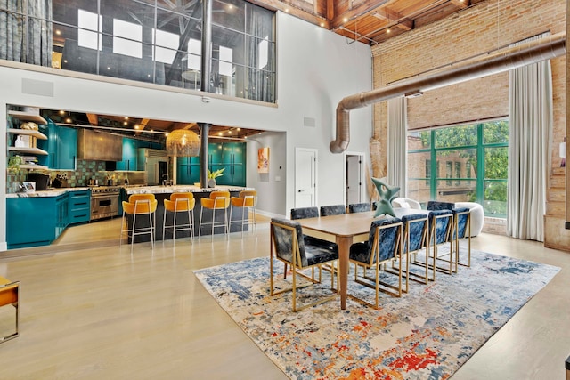 dining area featuring a towering ceiling and light hardwood / wood-style flooring