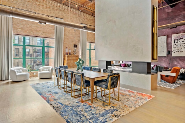 dining space with brick wall, hardwood / wood-style floors, and a high ceiling