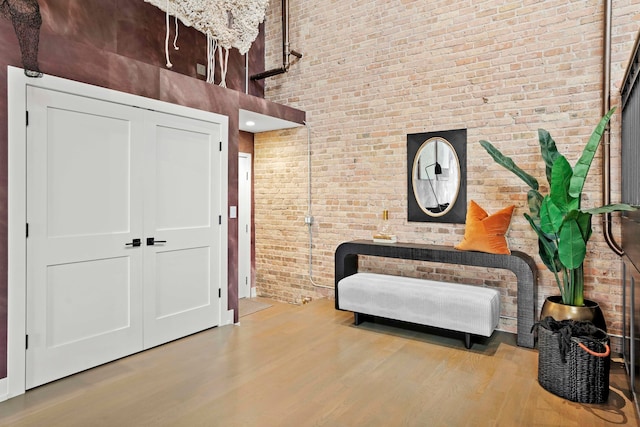 living area featuring wood-type flooring, brick wall, and a high ceiling