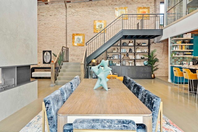 dining space featuring a high ceiling and brick wall