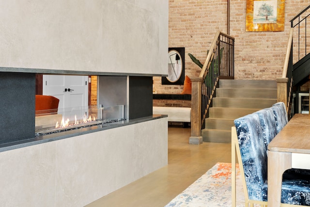 staircase with brick wall, concrete floors, and a high ceiling