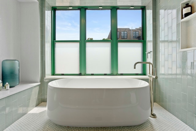 bathroom with tile patterned flooring, tile walls, and a washtub