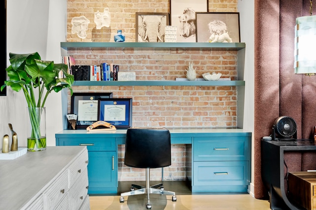 office space with brick wall and built in desk