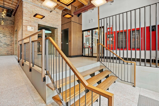 staircase with a towering ceiling and brick wall