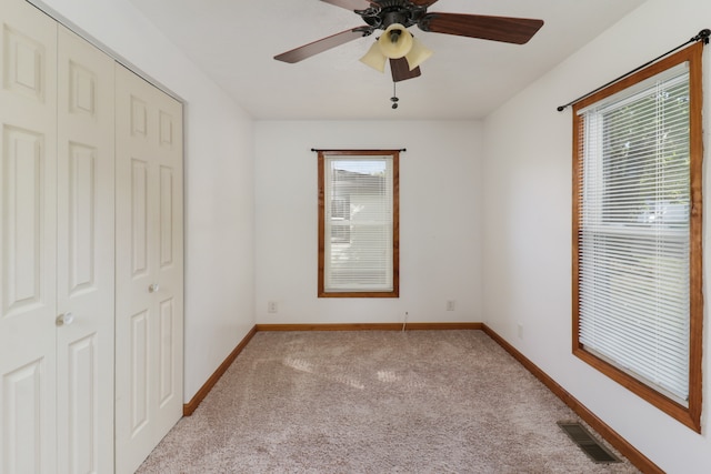 unfurnished bedroom with a closet, light colored carpet, and ceiling fan