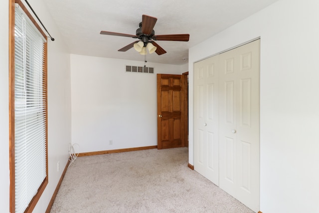 unfurnished bedroom featuring ceiling fan, a closet, and light colored carpet