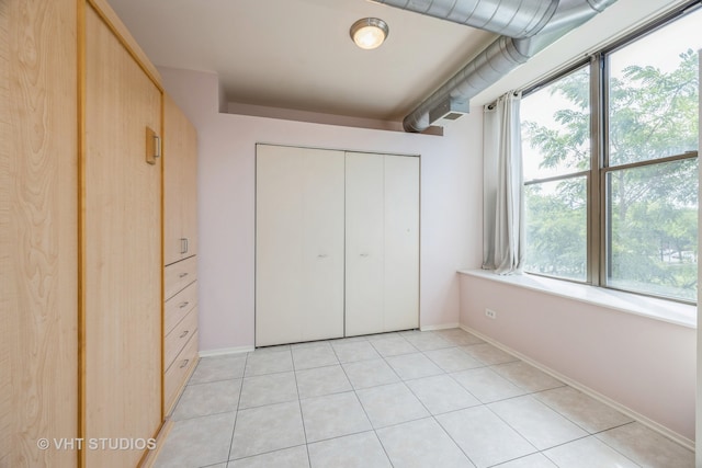 unfurnished bedroom featuring a closet, light tile patterned flooring, and multiple windows