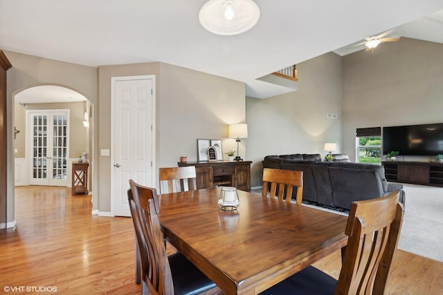 dining room featuring arched walkways, lofted ceiling, a ceiling fan, and light wood finished floors