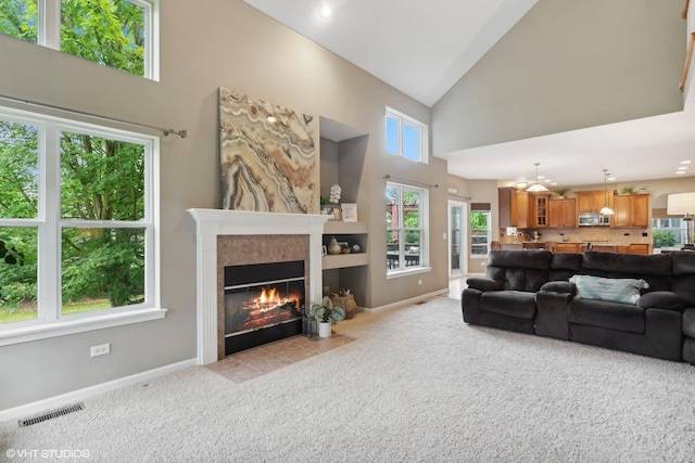 living area with baseboards, visible vents, a tile fireplace, and light carpet