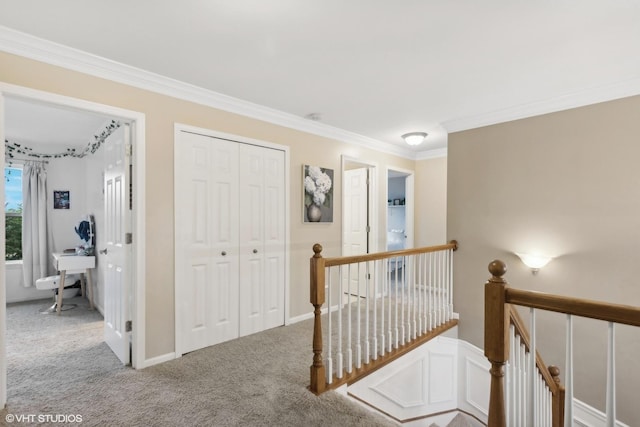 hall with an upstairs landing, carpet floors, and ornamental molding