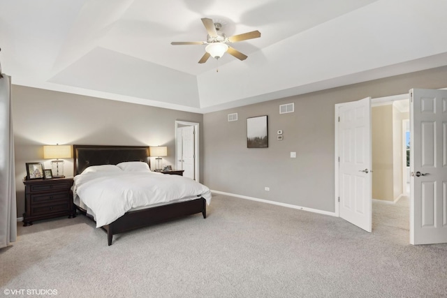 carpeted bedroom featuring a tray ceiling, baseboards, visible vents, and ceiling fan