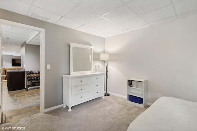 bedroom with light carpet, a paneled ceiling, and baseboards