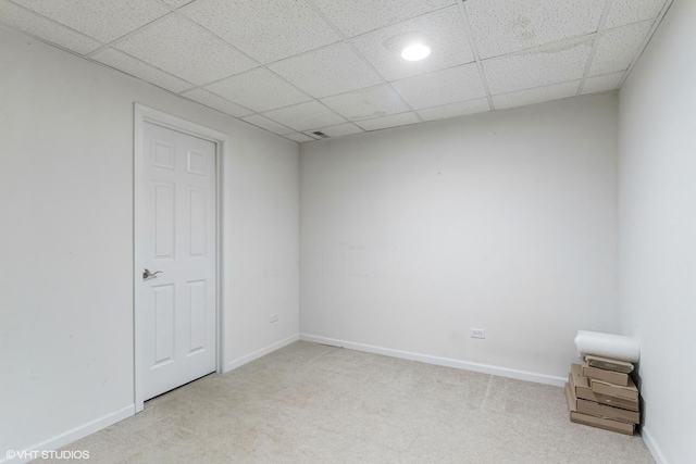 empty room with light colored carpet, baseboards, and a paneled ceiling