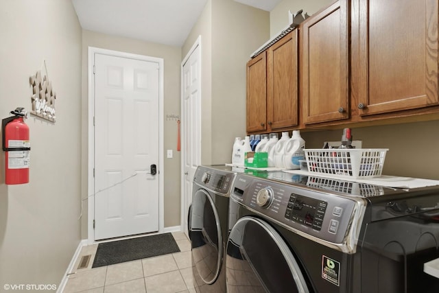 clothes washing area featuring light tile patterned flooring, cabinet space, baseboards, and separate washer and dryer