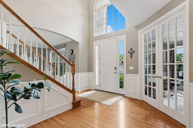 entryway with wood finished floors, arched walkways, and wainscoting