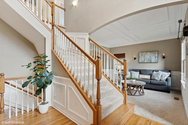 stairway featuring a decorative wall, wood finished floors, a wainscoted wall, and arched walkways