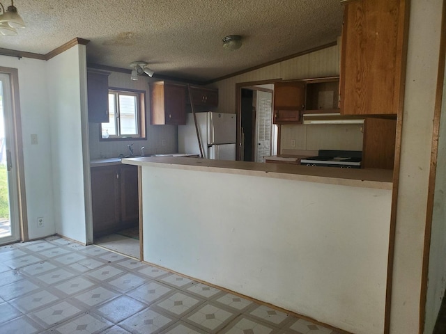 kitchen with crown molding, kitchen peninsula, white fridge, and a textured ceiling