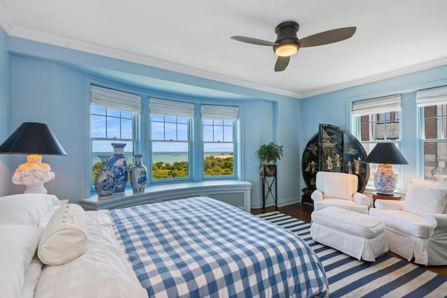 bedroom featuring hardwood / wood-style floors, multiple windows, a water view, and ceiling fan