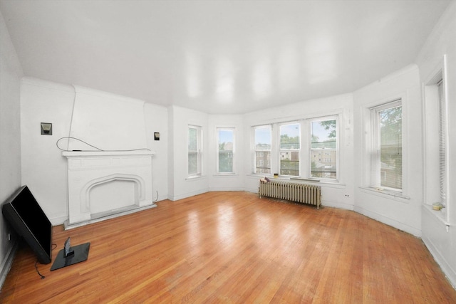 unfurnished living room with radiator heating unit and light wood-style flooring