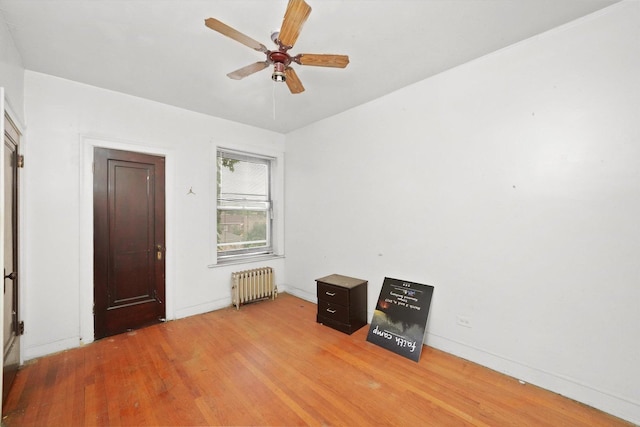 unfurnished bedroom with baseboards, radiator heating unit, and light wood-style floors