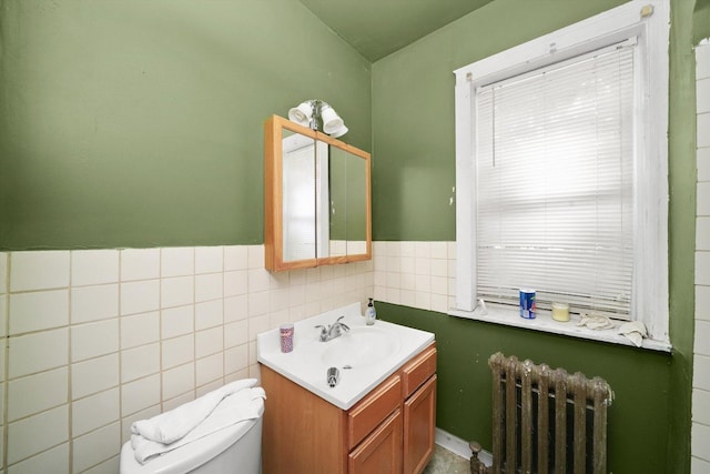 half bathroom with toilet, a wainscoted wall, tile walls, vanity, and radiator