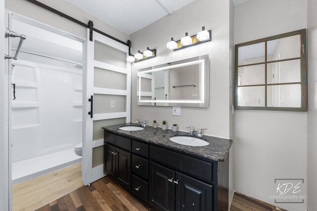 bathroom with walk in shower, hardwood / wood-style flooring, toilet, and double sink vanity