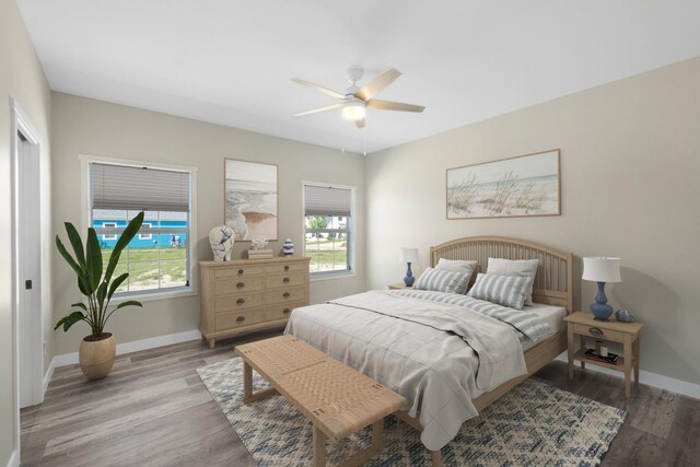 bedroom featuring ceiling fan, light hardwood / wood-style flooring, and multiple windows