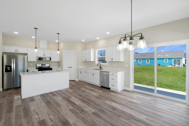 kitchen featuring appliances with stainless steel finishes, light wood-type flooring, and pendant lighting