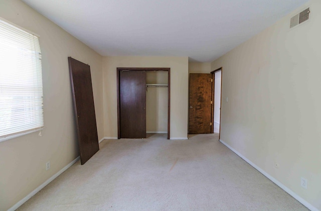 unfurnished bedroom featuring light carpet and a closet