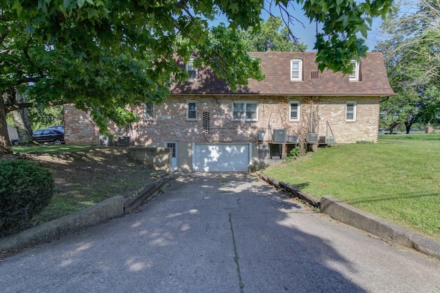 view of front of house featuring a garage, a front yard, and central air condition unit