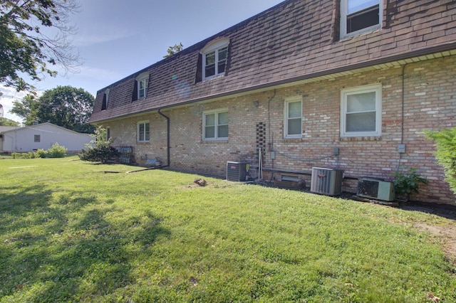 rear view of property with a lawn and central air condition unit