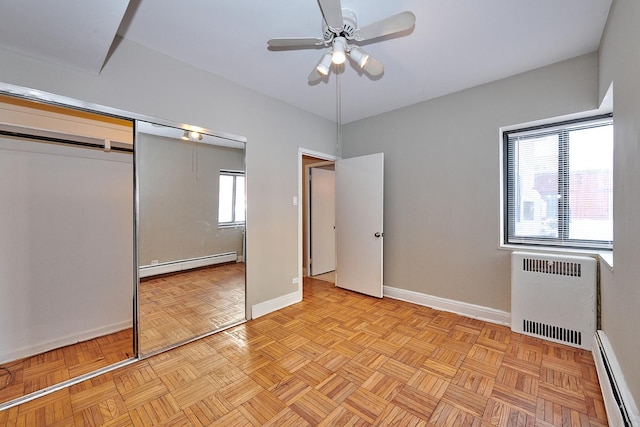 unfurnished bedroom featuring light parquet flooring, a baseboard heating unit, radiator heating unit, and a closet