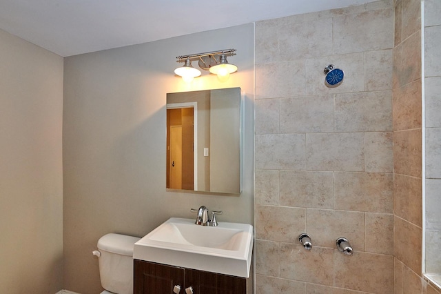 bathroom featuring vanity, toilet, and a tile shower