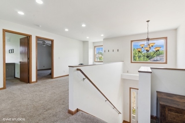 hallway with light carpet and a chandelier