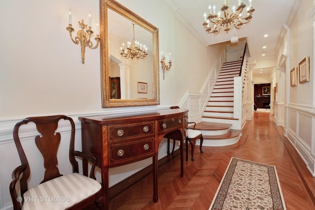 entryway featuring crown molding, a decorative wall, wainscoting, and a notable chandelier