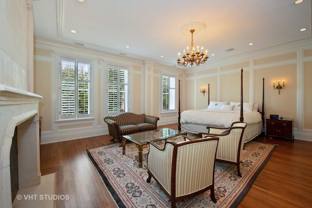 bedroom featuring a decorative wall, an inviting chandelier, wood finished floors, and crown molding