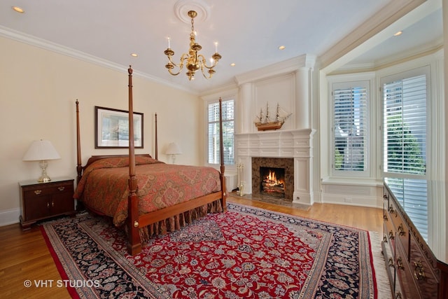 bedroom with a chandelier, a fireplace, wood finished floors, baseboards, and ornamental molding