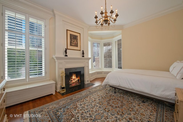 bedroom featuring an inviting chandelier, a fireplace, crown molding, and wood finished floors