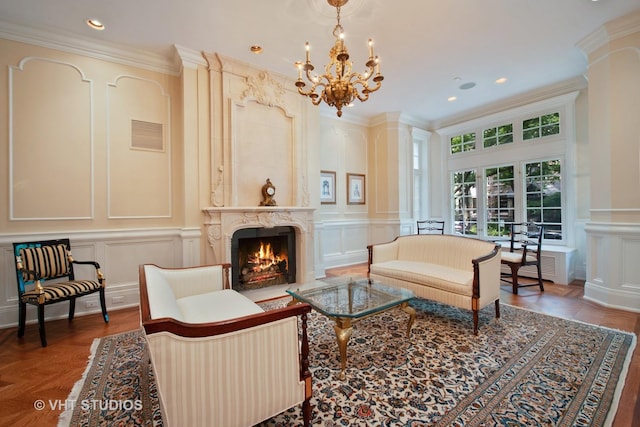 living area featuring decorative columns, ornamental molding, a fireplace, a chandelier, and a decorative wall