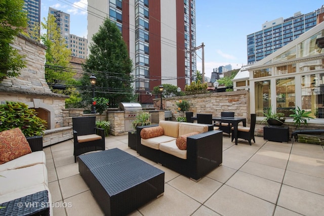 view of patio featuring a view of city, an outdoor living space with a fireplace, exterior kitchen, and a grill